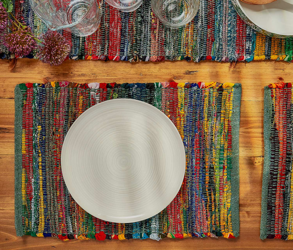 Colorful woven placemat with a white plate on a wooden table - Lollyfaf