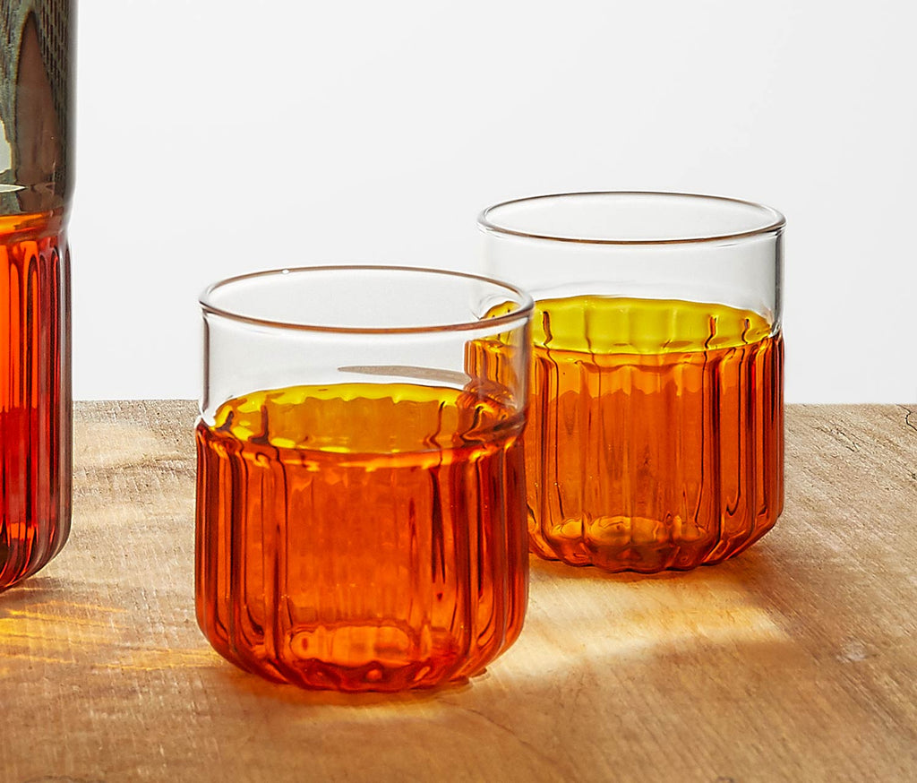 Two tone amber glass tumblers on a wooden surface - lollygag