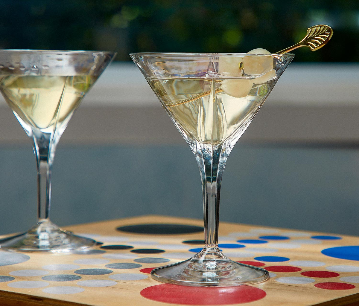 Clear RCR Calice crystal martini glass filled with a garnished cocktail next to bar tools