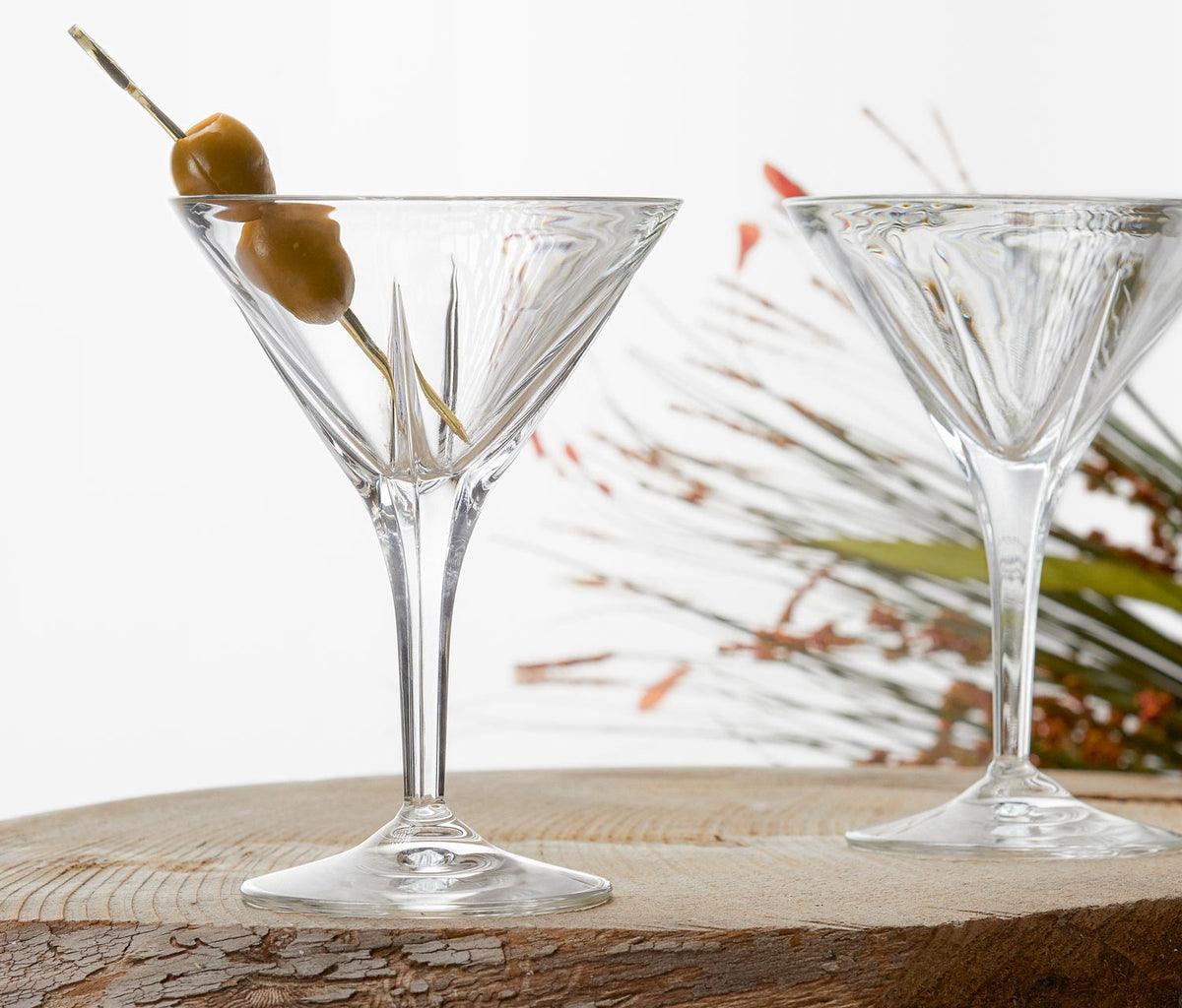 Set of 2 RCR Calice clear crystal martini glasses with etched geometric cut pattern on a wooden bar cart