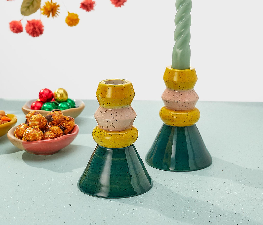 Colorful ceramic candle holders on a light surface with decorative elements in the background.