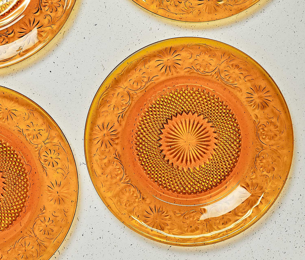 Decorative amber glass plates with intricate patterns on a light gray surface