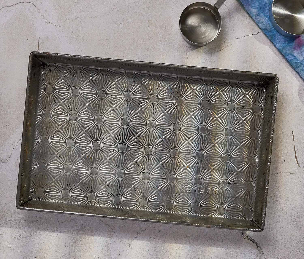 Vintage Metal baking tray with starburst embossed pattern on a light surface - lollygag